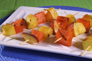 A plate of grilled fruit kebabs, which includes pineapple and watermelon