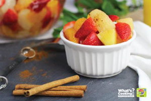 A bowl of fruit and cinnamon sticks