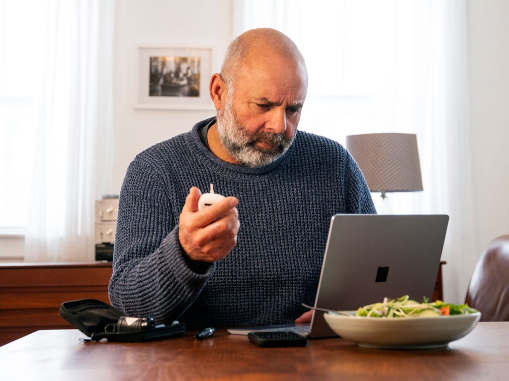Man with insulin monitor and pump at dinner table with salad