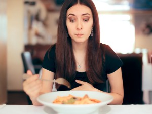 Woman who looks full with fork and bowl of food