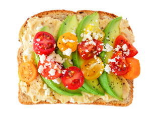 How the MIND Diet Promotes a Healthy Brain 2 An image of toast with hummus, avocado, tomato, and feta cheese.