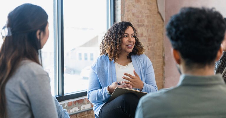 A mental health counselor speaks at a group session with patients.