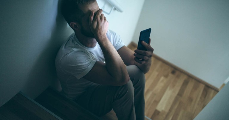 Distraught person with mobile phone in hand.